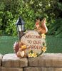 Squirrel Figurines Near a Welcome Sign and Lighted Lamp Post